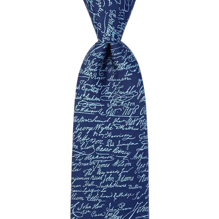 The Declaration of Independence Signers Silk Tie showcases a rich navy blue color adorned with white handwritten signatures scattered across the fabric, making it a perfect patriotic silk tie and an ideal gift for any history enthusiast.
