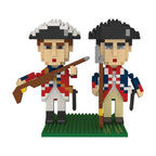 Two soldier figures from the Revolutionary War Soldiers Mini Blocks set stand on a green baseplate, dressed in 18th-century uniforms—one in a red coat with a rifle, the other in blue with a staff.