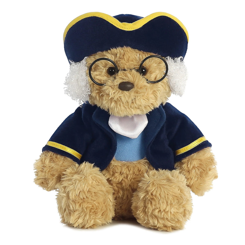 The Benjamin Franklin Stuffed Bear is a plush bear wearing a blue coat, round glasses, a blue and yellow tricorn hat, and white wig-like tufts.