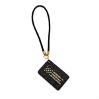 The "Life, Liberty, and the Pursuit of Happiness" Bag Charm features a black rectangle with thirteen gold stars in a circle, a gold clasp and black loop.