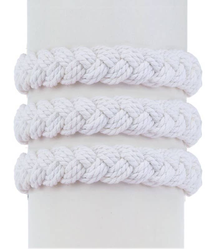Three White Sailor Knot Bracelets with thick, braided designs are displayed on a cylindrical stand, evoking timeless maritime heritage.