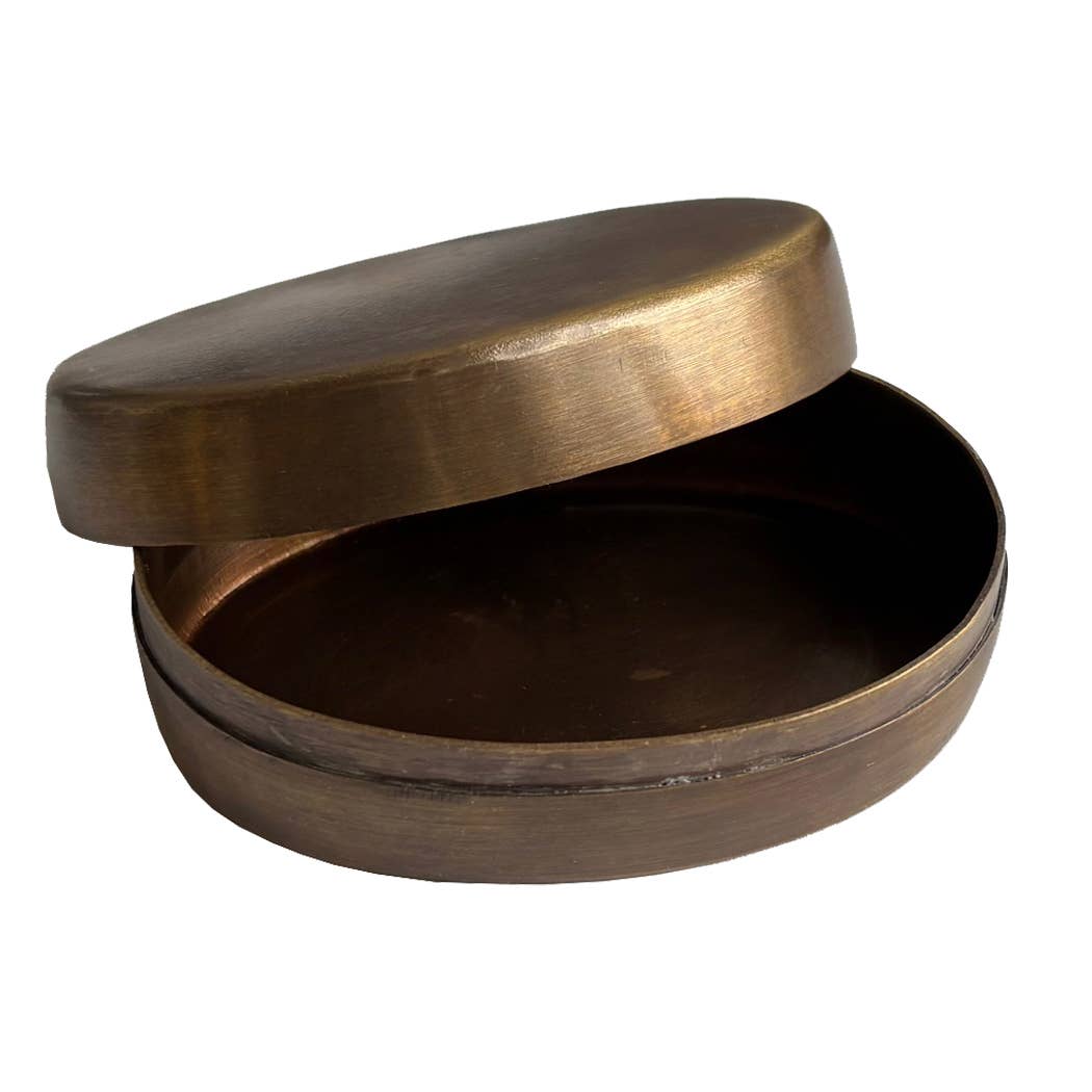 The Sailing Ship Pill Box is a round, shallow antiqued brass container with a matching lid slightly open, showing its empty interior. Its smooth metal surface features a gently brushed texture for an elegant look.