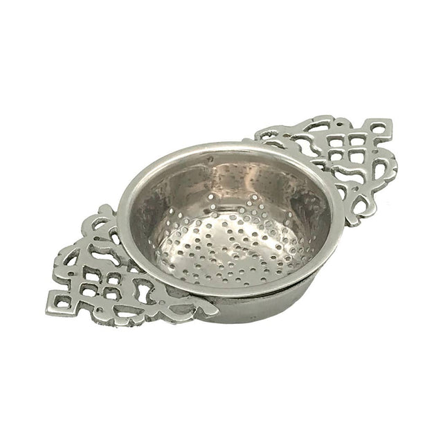 The Nickel Plated Tea Strainer features vintage styling with a round perforated bowl and ornate handles on both sides, making it perfect for enjoying loose-leaf tea with its intricate cut-out design.