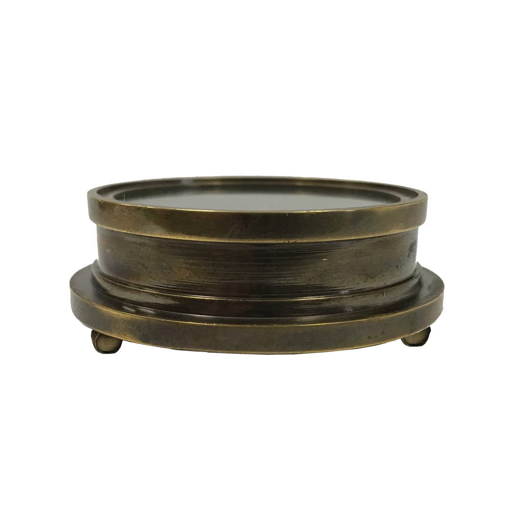 An Antiqued Solid Brass Compass with a round, vintage design and three small feet, displayed against a white background; its thick brass frame recalls the timeless style of antique navigation instruments.
