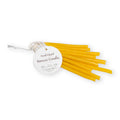 A bundle of thin, yellow Small Hand Dipped Beeswax Taper Candles tied with a round tag.
