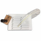 A white feather quill rests on penmanship practice paper beside an ink bottle in a wooden stand—an elegant set included in the Calligraphy Kit.