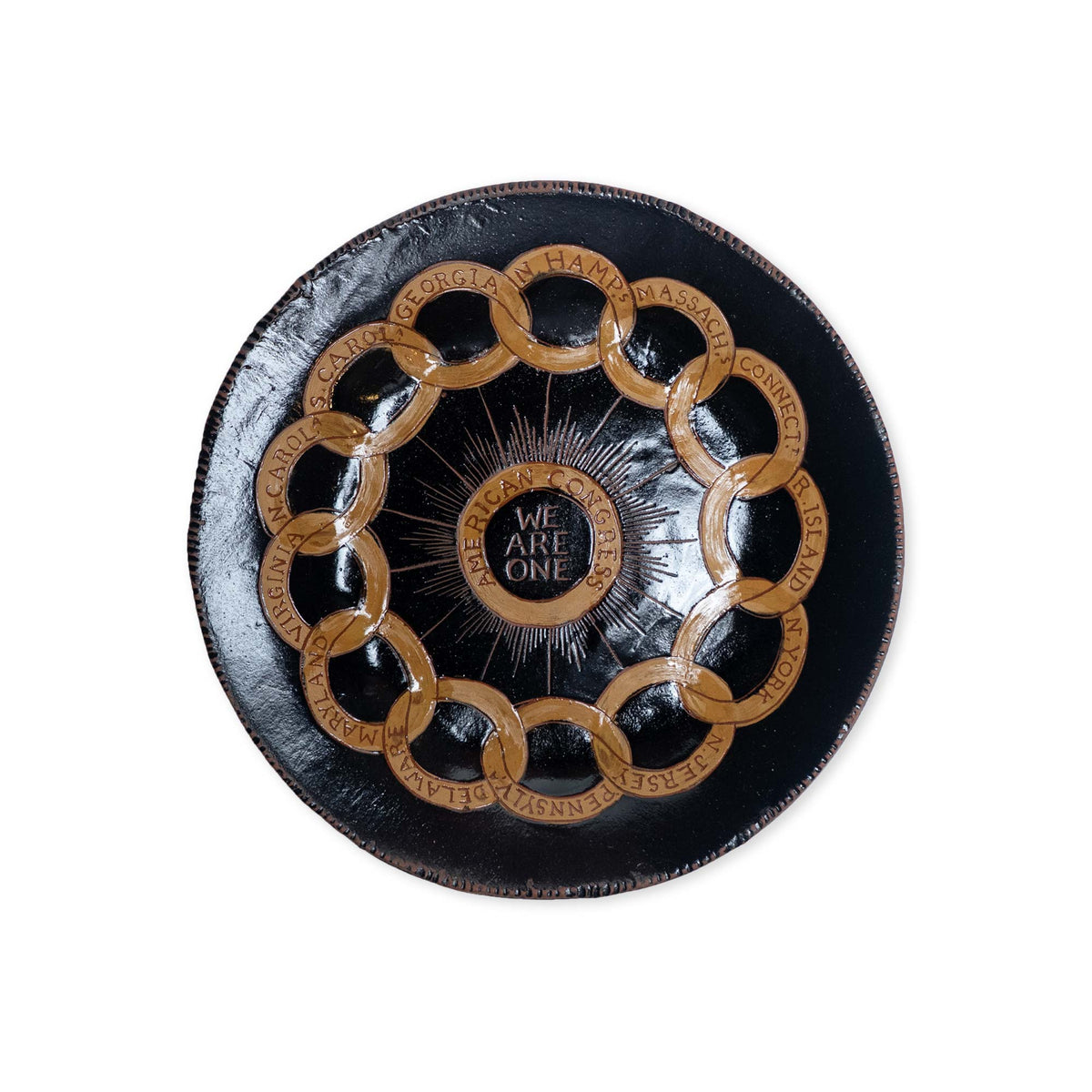 The Chain of States Plate, Black features handcrafted black ceramic with gold interlocking rings, state names, “We Are One” at the center, and a sunburst design inspired by the American Revolution.