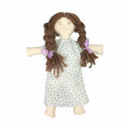 The Colonial Doll Kit lets you make a handmade cloth doll with brown yarn braids tied in purple ribbons and a white dress with a green floral print—a charming choice for history lovers and craft enthusiasts.