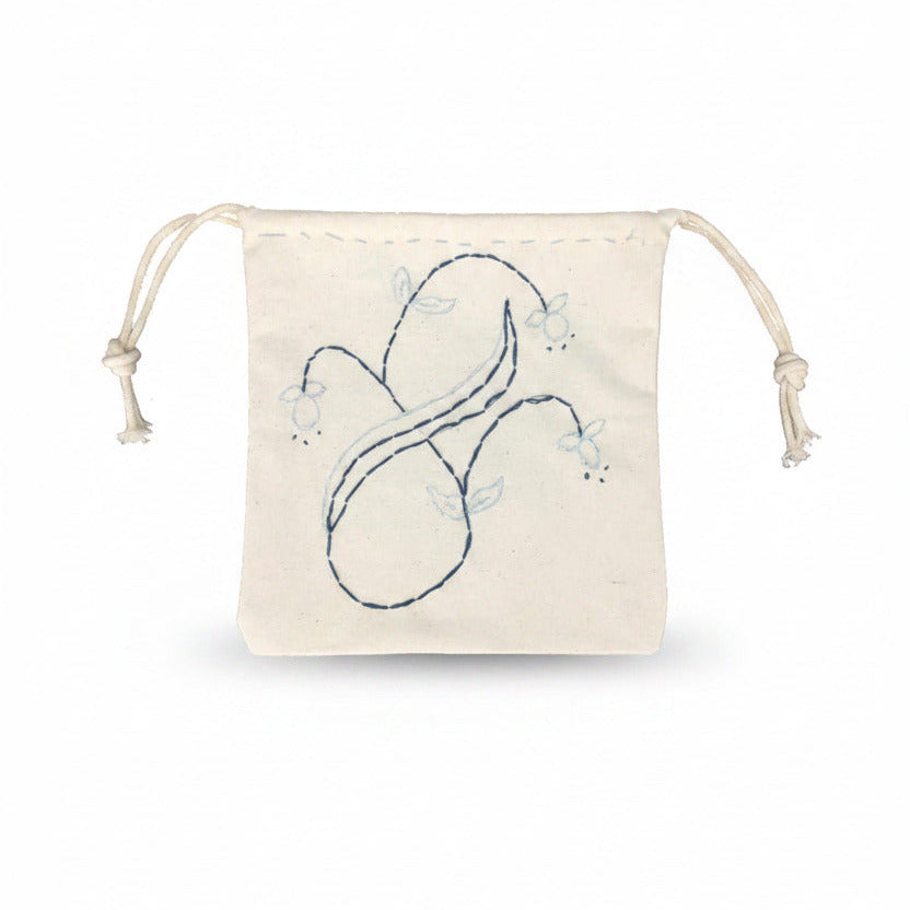 The Embroidery Kit includes a small off-white drawstring pouch with a light blue hand-stitched floral and leaf design on the front, plus two knotted drawstrings—ideal for showcasing beginner embroidery skills.