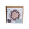 Lavender Wreath Embroidery Kit in a cardboard box, featuring an image of the finished project with embroidery floss skeins visible underneath, honoring American needlework traditions.