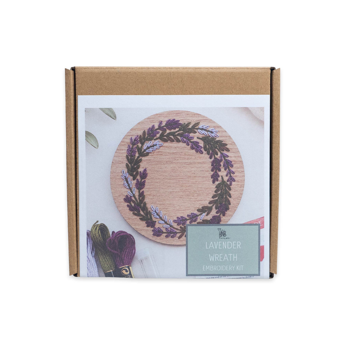 Lavender Wreath Embroidery Kit in a cardboard box, featuring an image of the finished project with embroidery floss skeins visible underneath, honoring American needlework traditions.