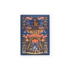 Hamilton Playing Cards—a box of premium Broadway musical merchandise—features an ornate gold, blue, and red decorative design with a striking silhouette and “Hamilton Playing Cards” text on the front, making it a must-have collectible for any fan.