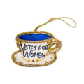 The Votes for Women Teacup Ornament is a teacup and saucer-shaped decoration adorned with blue and gold accents, featuring the words "Votes for Women" on the cup. Complete with a gold string for hanging, this meaningful women’s rights ornament makes a unique addition to your tree or display.