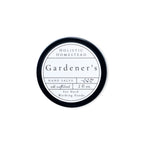 A round tin of Holistic Homestead Gardener’s Hand Salve with a white label featuring the text all natural, 2 fl oz, For Hard Working Hands.