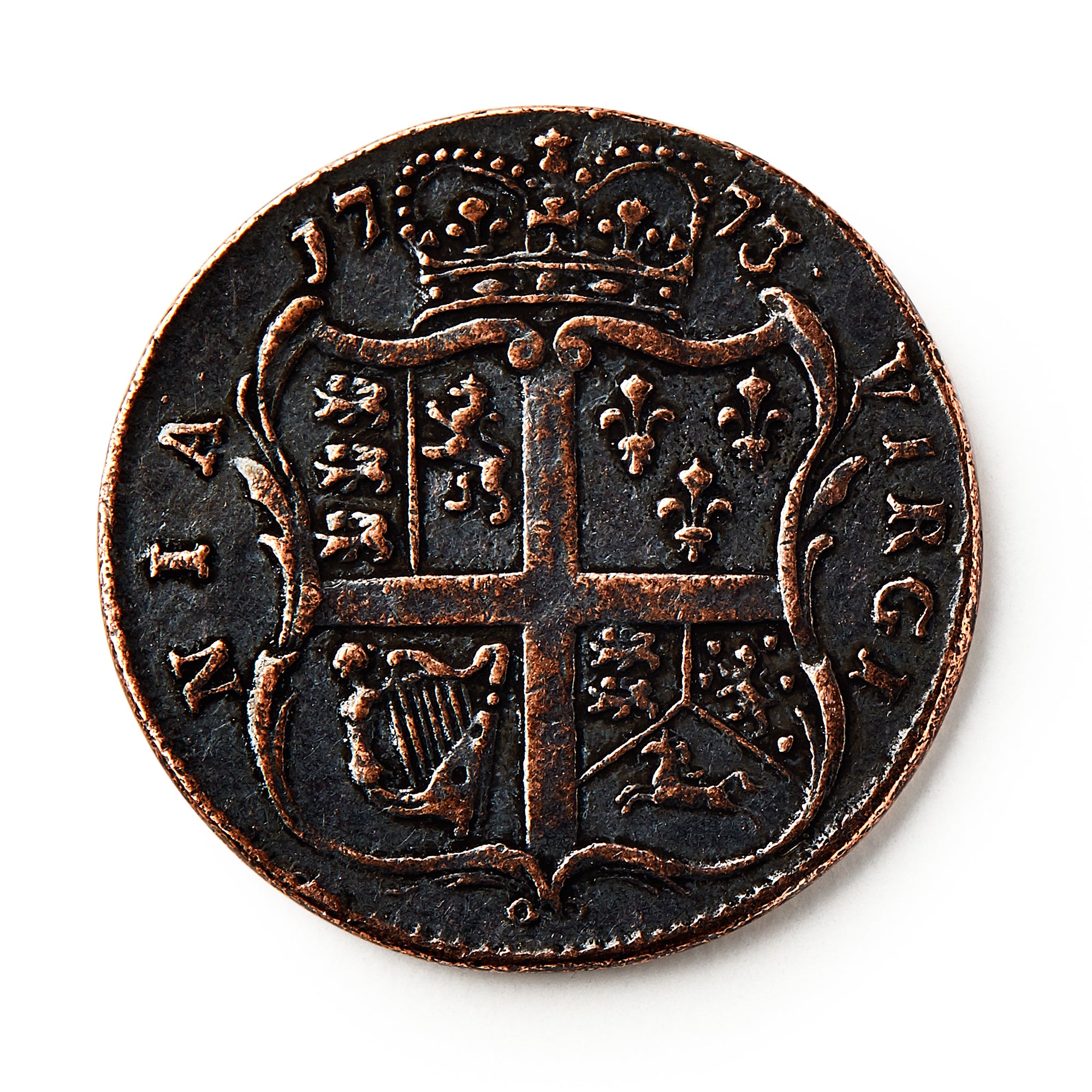 A 1773 Virginia Halfpenny with a crowned shield, heraldic symbols, and a cross is shown against a white background. The worn coin displays raised text and details and reflects British colonial currency design.