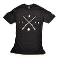 The 1775 Militia T-Shirt is a black tee with two crossed Pennsylvania muskets, a star above, 1775 on each side, and a small pine tree below—all in bold white print.