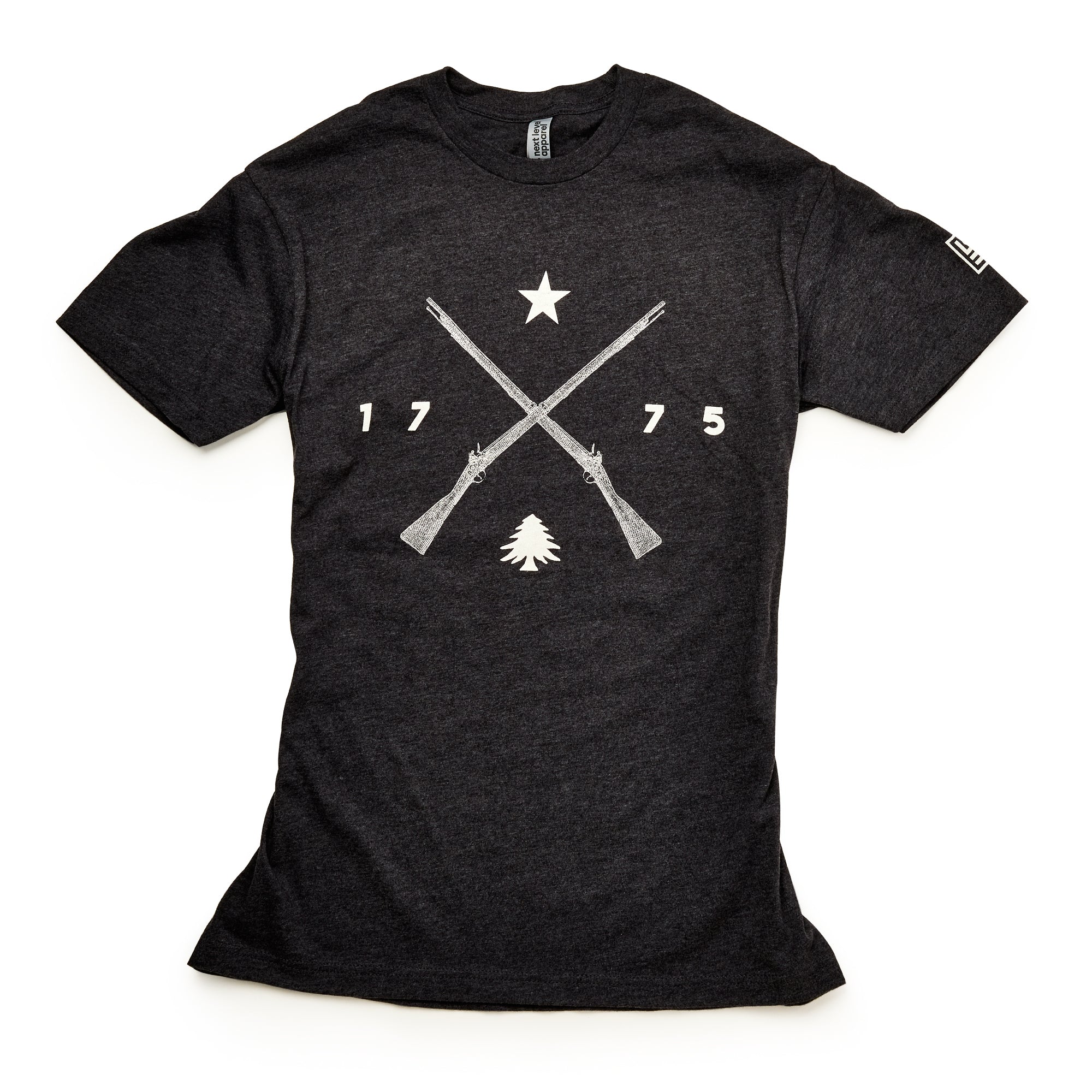 The 1775 Militia T-Shirt is a black tee with two crossed Pennsylvania muskets, a star above, 1775 on each side, and a small pine tree below—all in bold white print.