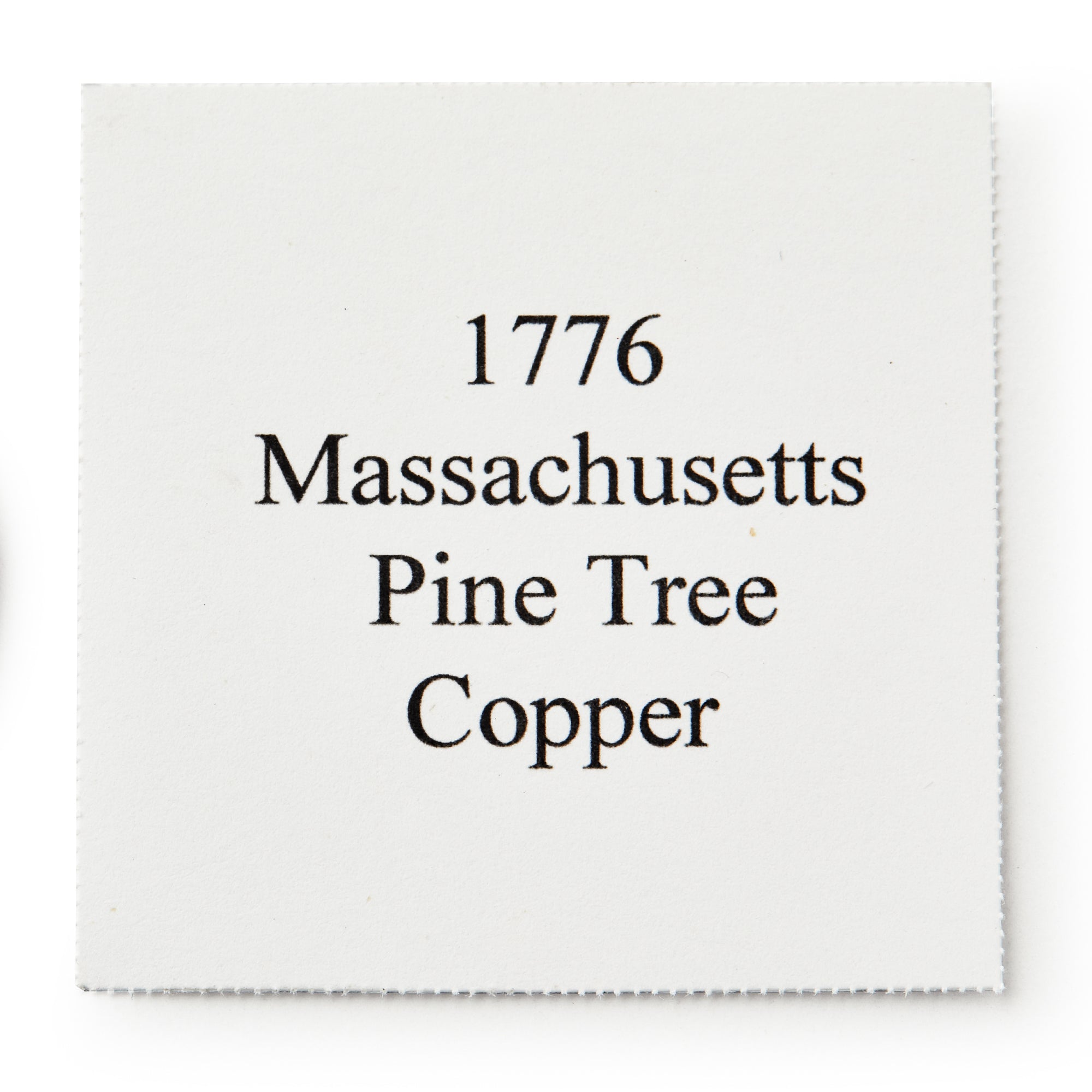A white square paper with black text that reads: 1776 Pine Tree Copper Coin, a symbol of colonial independence and early American currency.