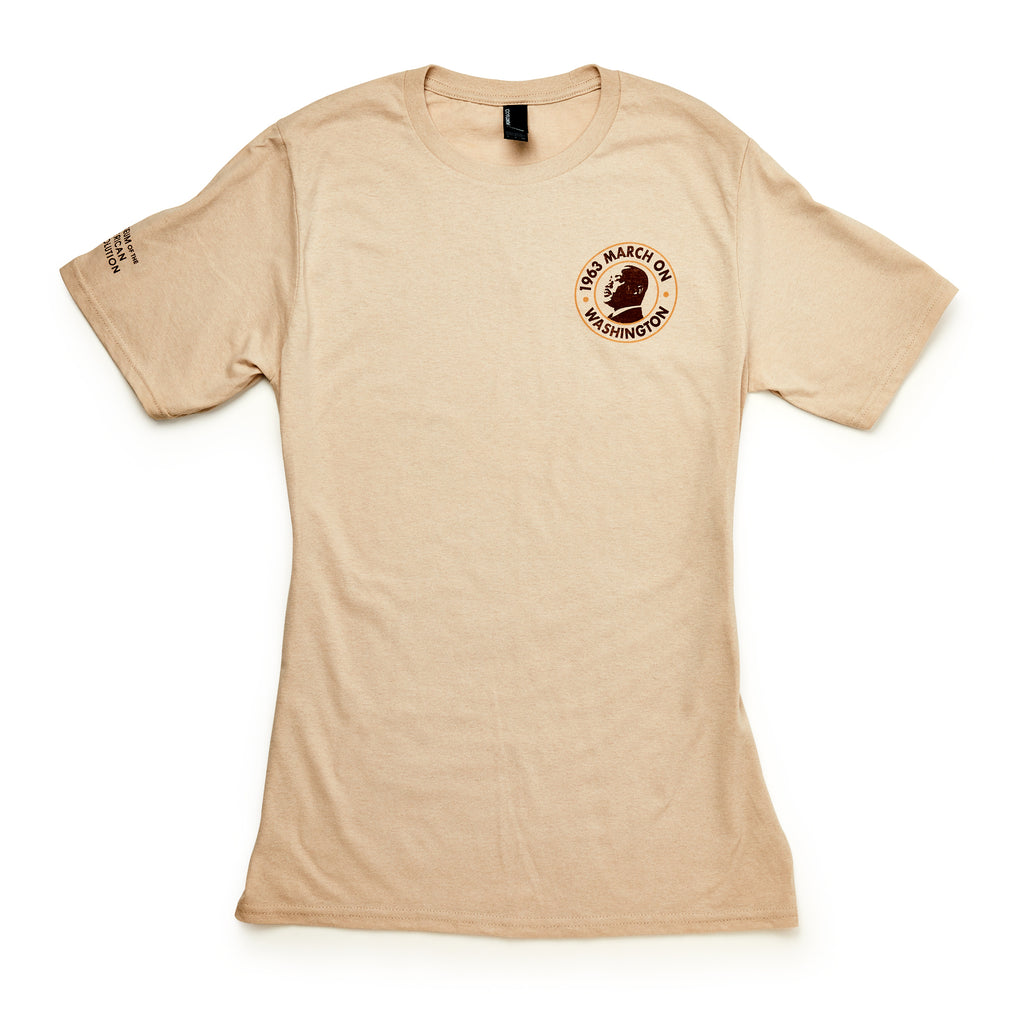 The March on Washington T-Shirt, Natural, features a small round "1963 March on Washington" civil rights logo and an image of Martin Luther King Jr. on the left chest, plus text near the right shoulder. Short sleeves and neutral beige color.