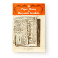 A plastic bag with an orange and white header labeled "Benjamin Franklin Paper Money" holds colonial currency replicas and a black-and-white portrait.