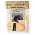 The Boat Kit includes a precut wood hull, a sail to sew, and an instruction booklet featuring a child by the water. Labeled "You Can Learn... Basic skills from Early American Life.