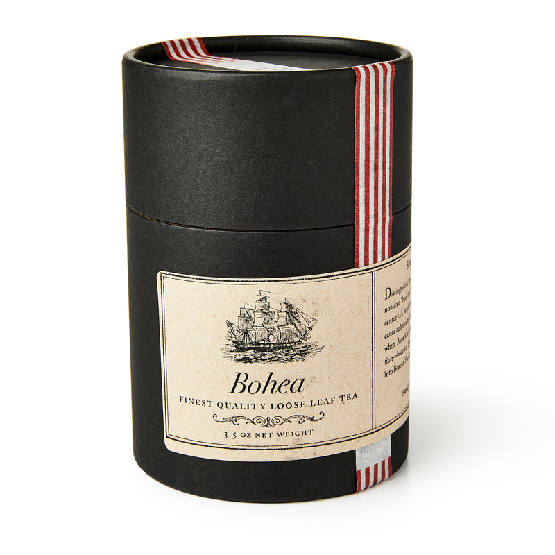 A black cylindrical tin labeled "Bohea Loose Leaf Tea," 3.5 oz, with a ship illustration referencing the Boston Tea Party, finished with a red and white striped ribbon.