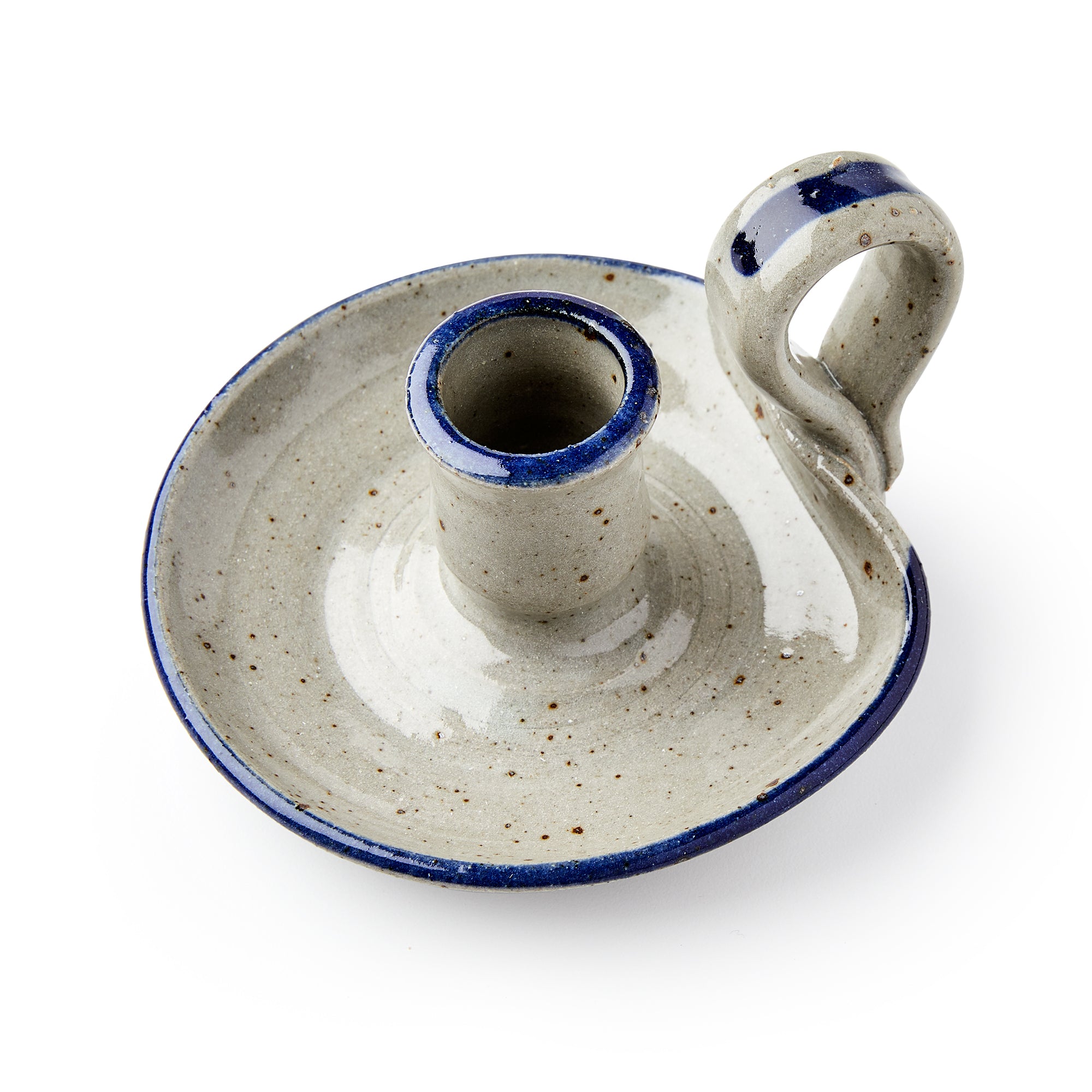The Stoneware Candle Holder is a rustic, handcrafted piece with a round base, short central socket, curved handle, light gray finish, blue rim, and speckled glaze.