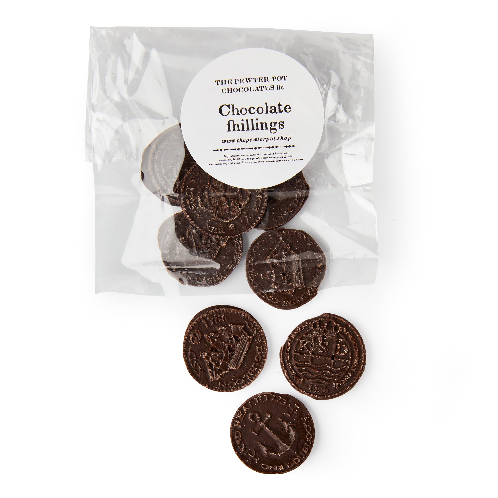 A clear bag labeled "Chocolate Shillings" holds several coin-shaped chocolates with antique-style ship and anchor designs. Four coins are displayed outside, featuring detailed imprints reminiscent of classic colonial currency.