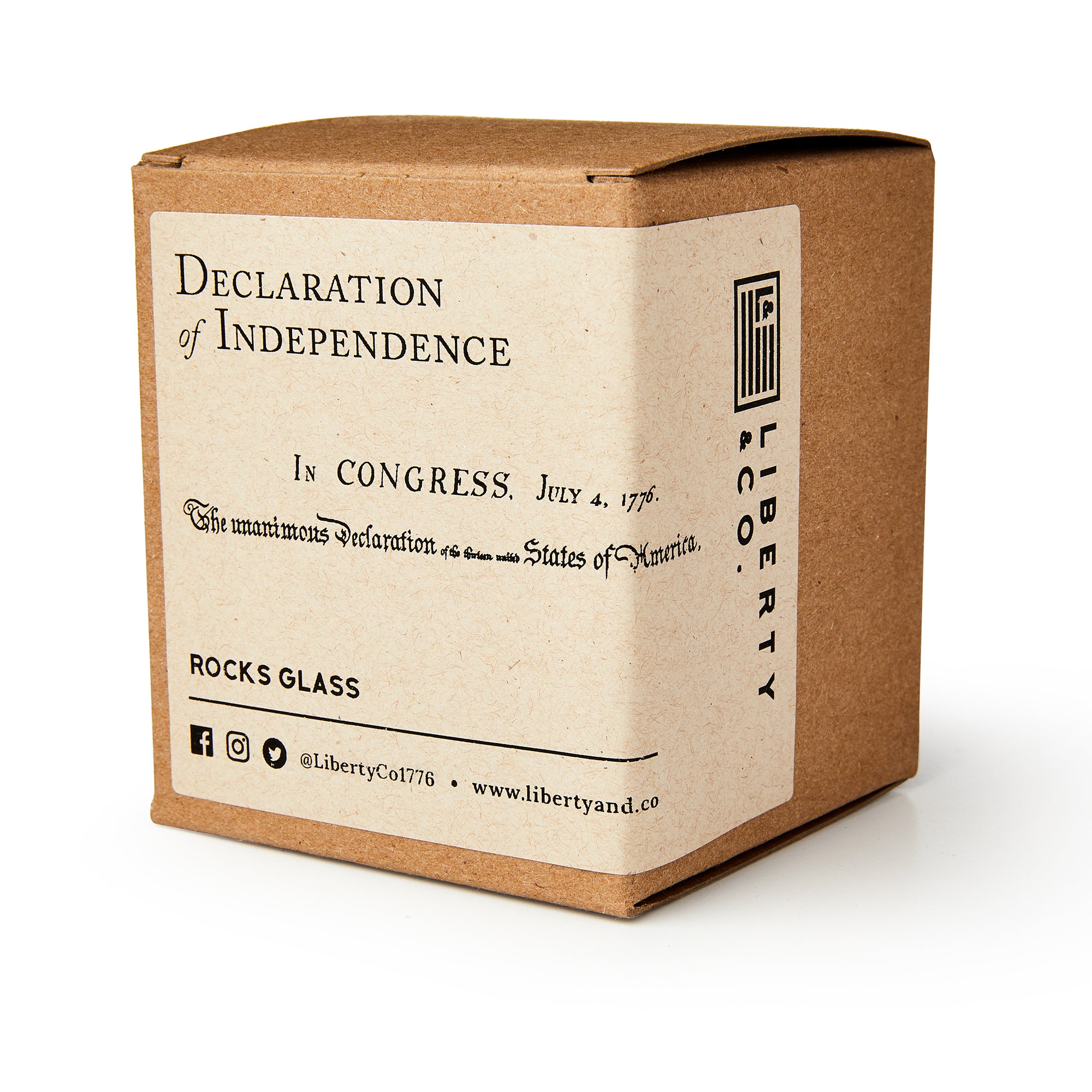 A brown box labeled "Declaration of Independence Whiskey Glass" features vintage text, Liberty & Co. branding, and social media info—making it a perfect patriotic gift for any whiskey glass enthusiast.