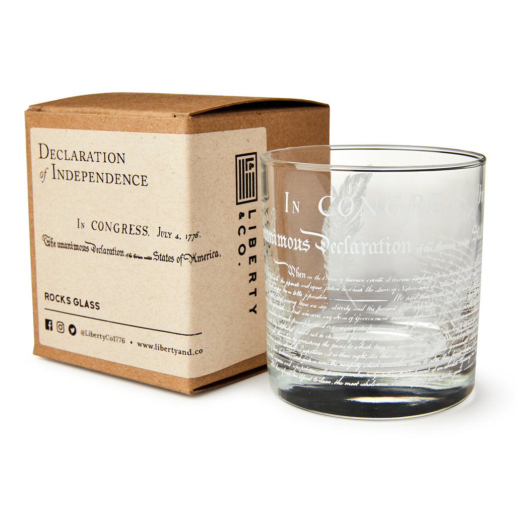The Declaration of Independence Whiskey Glass sits beside a brown box labeled "Declaration of Independence and Liberty," creating a unique patriotic gift with branded packaging and historical details.