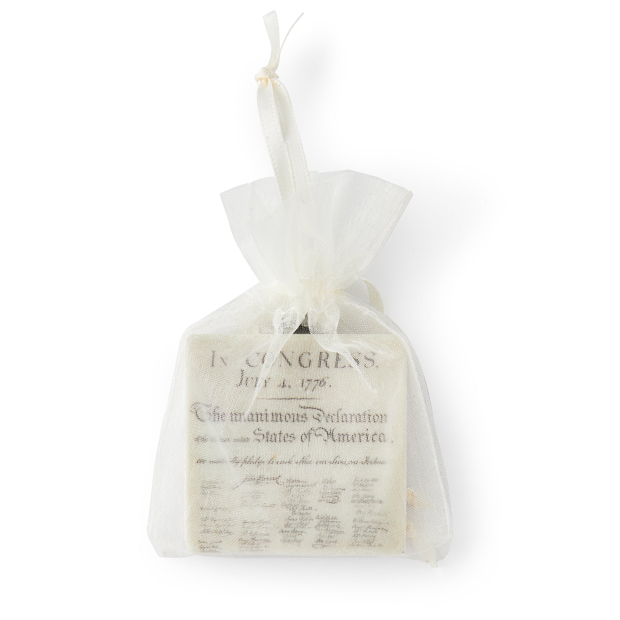 A small white mesh gift bag containing the Declaration of Independence Ornament—a stone ornamment printed with the historic text and signatures.