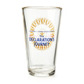 The Declaration's Journey Pint Glass is a clear glass pint with a gold rim, featuring the Museum of the American Revolution logo and “The Declaration’s Journey” in blue and gold on the front, celebrating the Semiquicentennial exhibition.