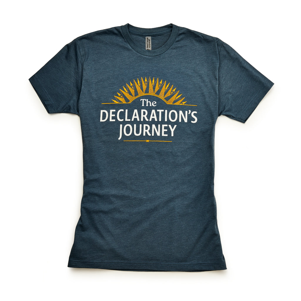 The Declaration's Journey T-Shirt features white "The Declaration’s Journey" text below a yellow sunburst on blue, displayed flat on white—ideal for commemorating the Declaration of Independence Semiquicentennial exhibition.