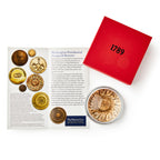 A display with a historical card features images of presidential inaugural buttons, a red box labeled 1789, and the GW Linked States Paperweight in a clear case with an eagle design.