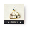 The George Washington Tent Pin is a white tent enamel pin with a blue flag and "G W" on the front, inspired by Washington's Revolutionary War tent. Presented on a collectible pin card with star accents.