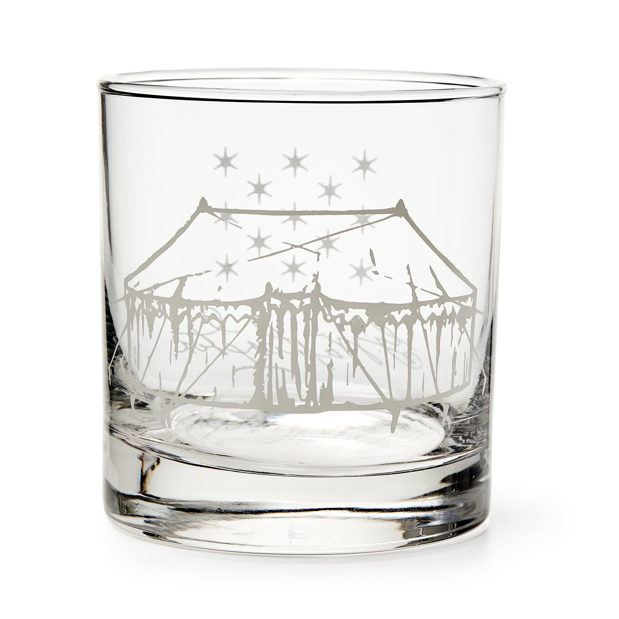 The George Washington Tent Whiskey Glass is a clear tumbler etched with a large circus tent and stars, inspired by the original whiskey glass. Displayed empty against a white background.