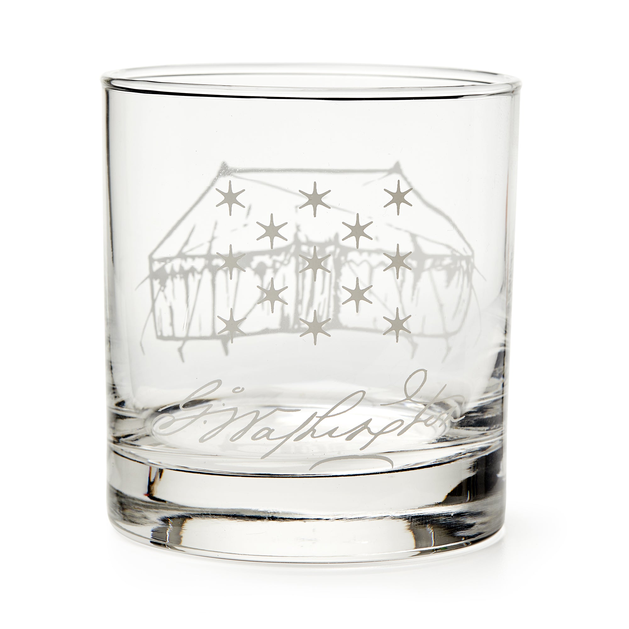 The George Washington Tent Whiskey Glass features a clear glass design engraved with a starry tent and cursive signature, reminiscent of classic Washington whiskey glasses, displayed empty against a white background.