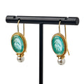 Glass Intaglio and Pearl Earrings, Teal—these elegant earrings feature oval teal glass intaglios and dangling pearls, inspired by colonial-era jewelry, displayed on a black T-shaped stand with gold-plated earwires.