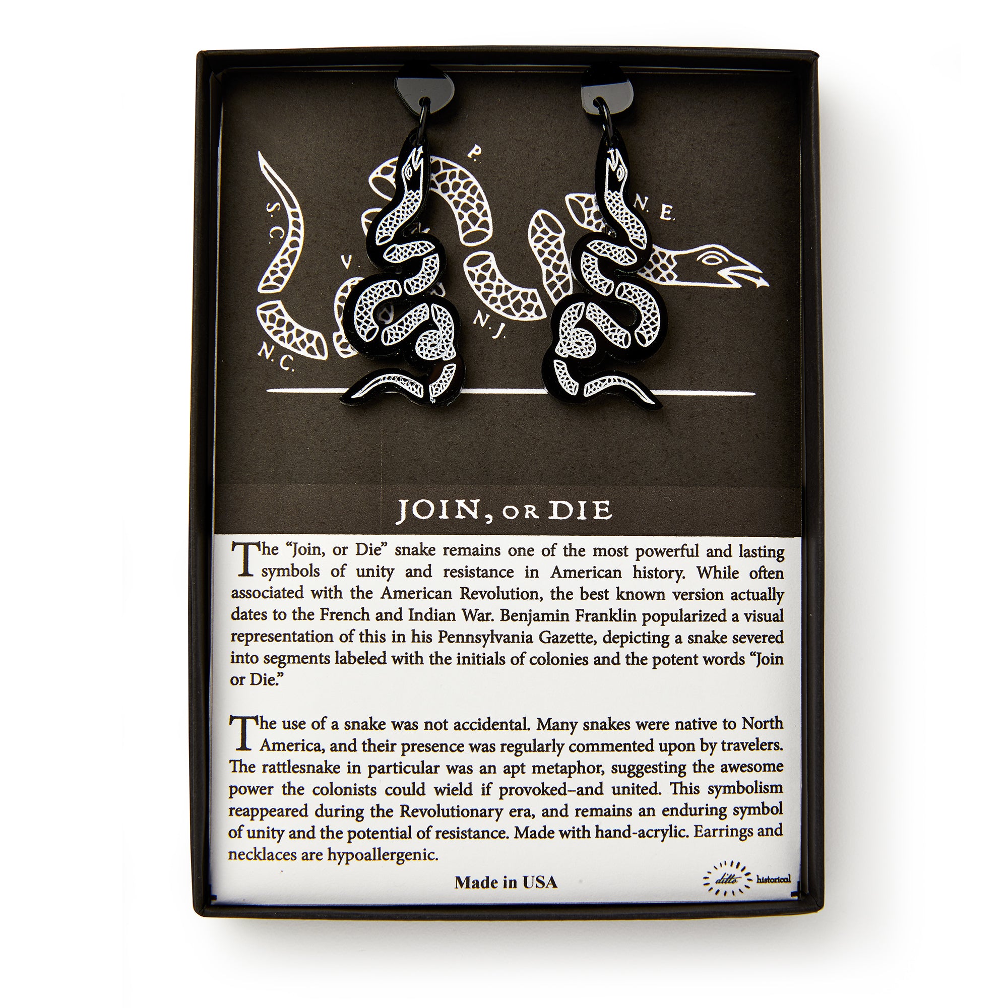 Black Snake Earrings, shaped like snakes with white detailing, are shown in a box featuring a segmented snake and text on the historic “Join, or Die” symbol and colonial unity from the American Revolution.