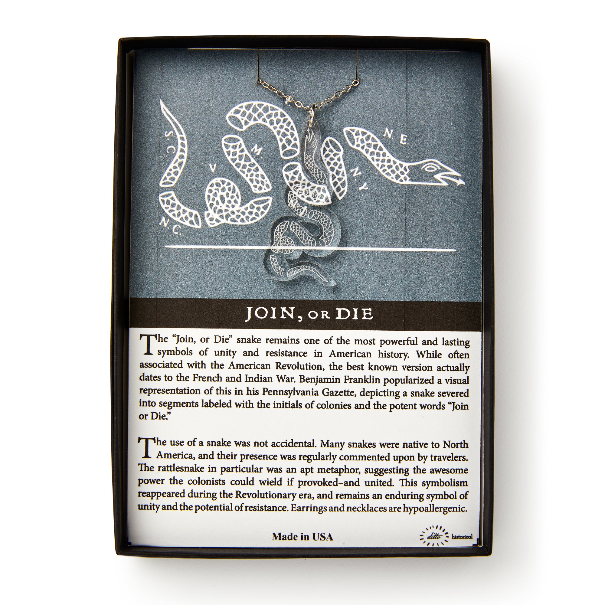 A boxed jewelry set, the Clear Snake Necklace, displays a silver pendant shaped like the iconic segmented snake with directional letters in the background and a description emphasizing its historical message of unity and resistance.