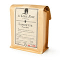 A brown paper bag labeled Lafayette Whole Bean Coffee, West Java Blue Sunda French roast, with tasting notes and a red expiration date stamped Mar 15 2026 on the front.