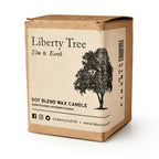 A brown cardboard box labeled Liberty Tree Candle features a black tree illustration and social media info, highlighting the hand-poured elm and earth soy blend scent made in Pennsylvania.