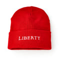 A bright red Liberty Cap Beanie, featuring "LIBERTY" embroidered in bold white letters on the front fold, combines American freedom and modern comfort, shown against a white background.