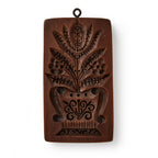 The Christopher Ludwick Gingerbread Mold, Small, Flower features a rectangular wooden design with a carved stylized flower bouquet in a vase and a hanging ring.