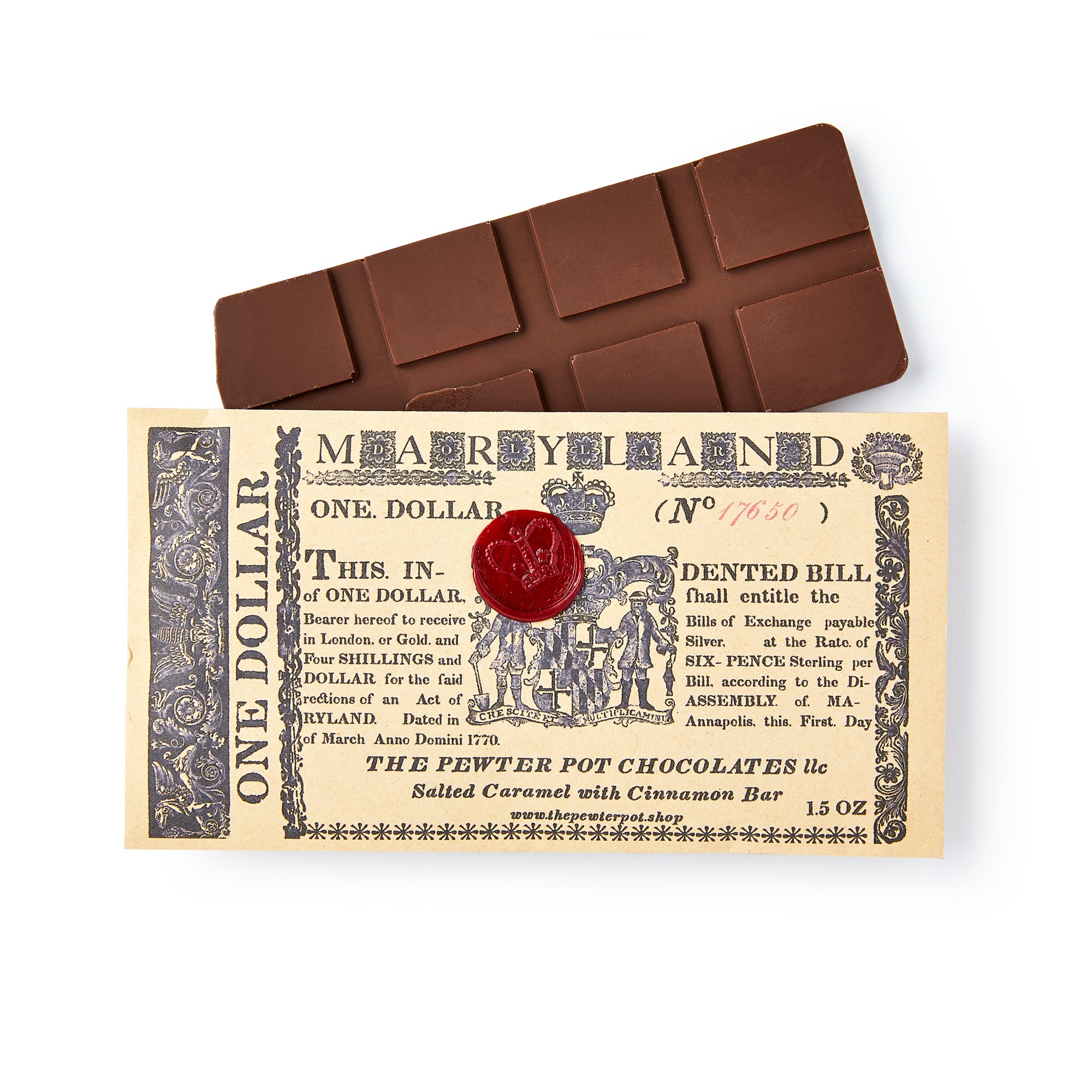 A Maryland Chocolate Bar sits atop a replica of an old Maryland one-dollar bill with ornate details and a red wax seal, while its label features the product's name and flavor: salted caramel dark chocolate with cinnamon.