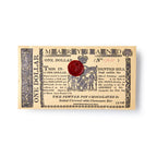A vintage-style Maryland Chocolate Bar wrapper features ornate black text, designs, a red wax seal at the center, and "Salted Caramel with Cinnamon Bar" at the bottom.