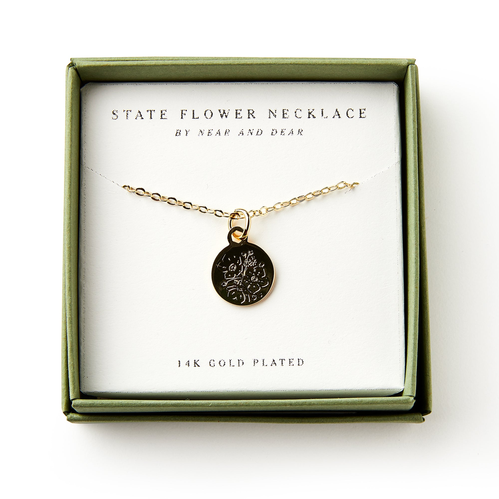 The Mountain Laurel Necklace features a gold-plated, floral-engraved round pendant in a green box labeled "State Flower Necklace," celebrating Pennsylvania's state flower and botanical artistry.