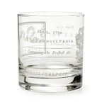 The Join or Die Whiskey Glass is a clear tumbler engraved with "May 9, 1754," Pennsylvania, and vintage motifs inspired by Benjamin Franklin’s iconic design—a unique tribute to American history.