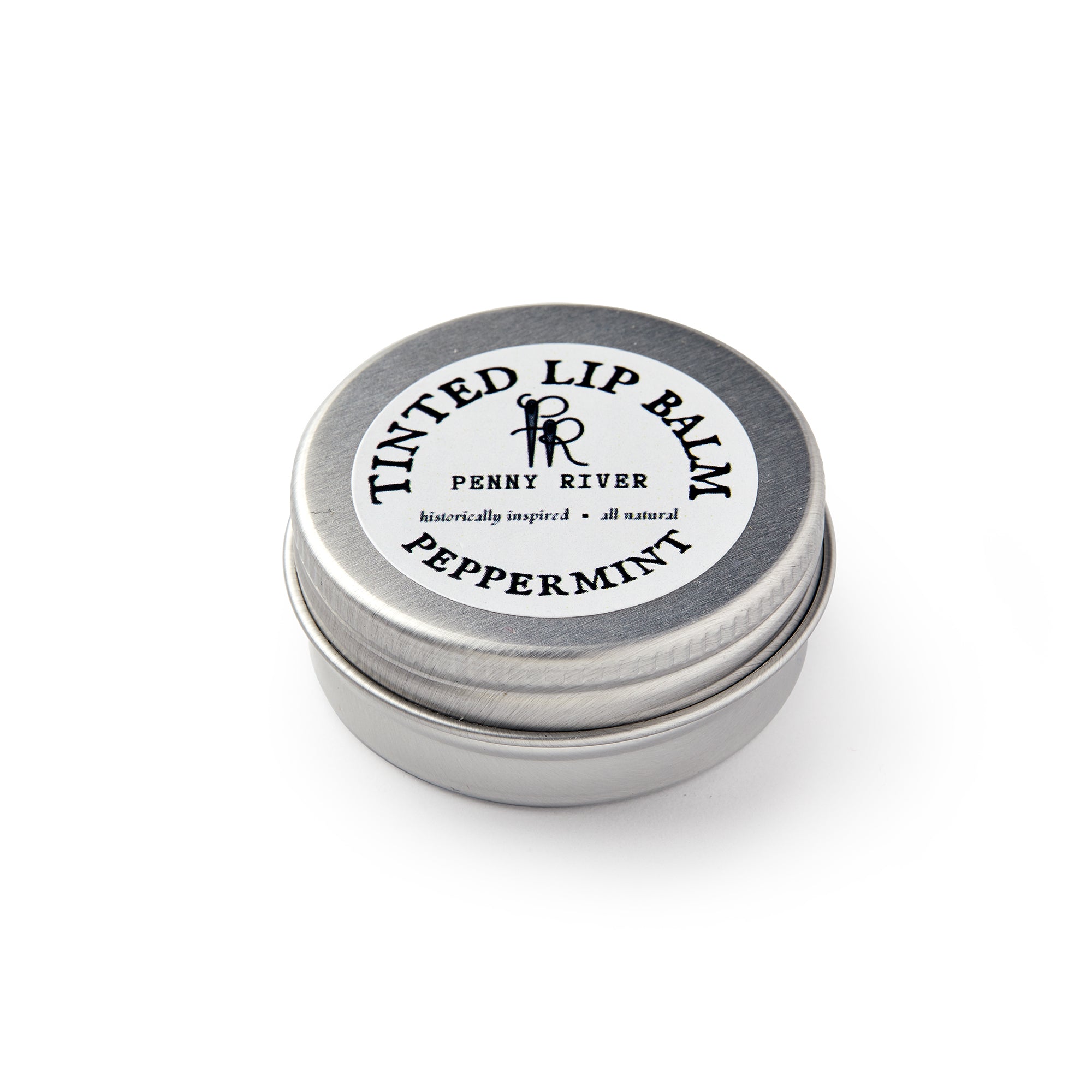 A small round metal tin labeled Lip Balm from Penny River features a simple black and white lid design and provides moisturizing care with a refreshing peppermint scent.
