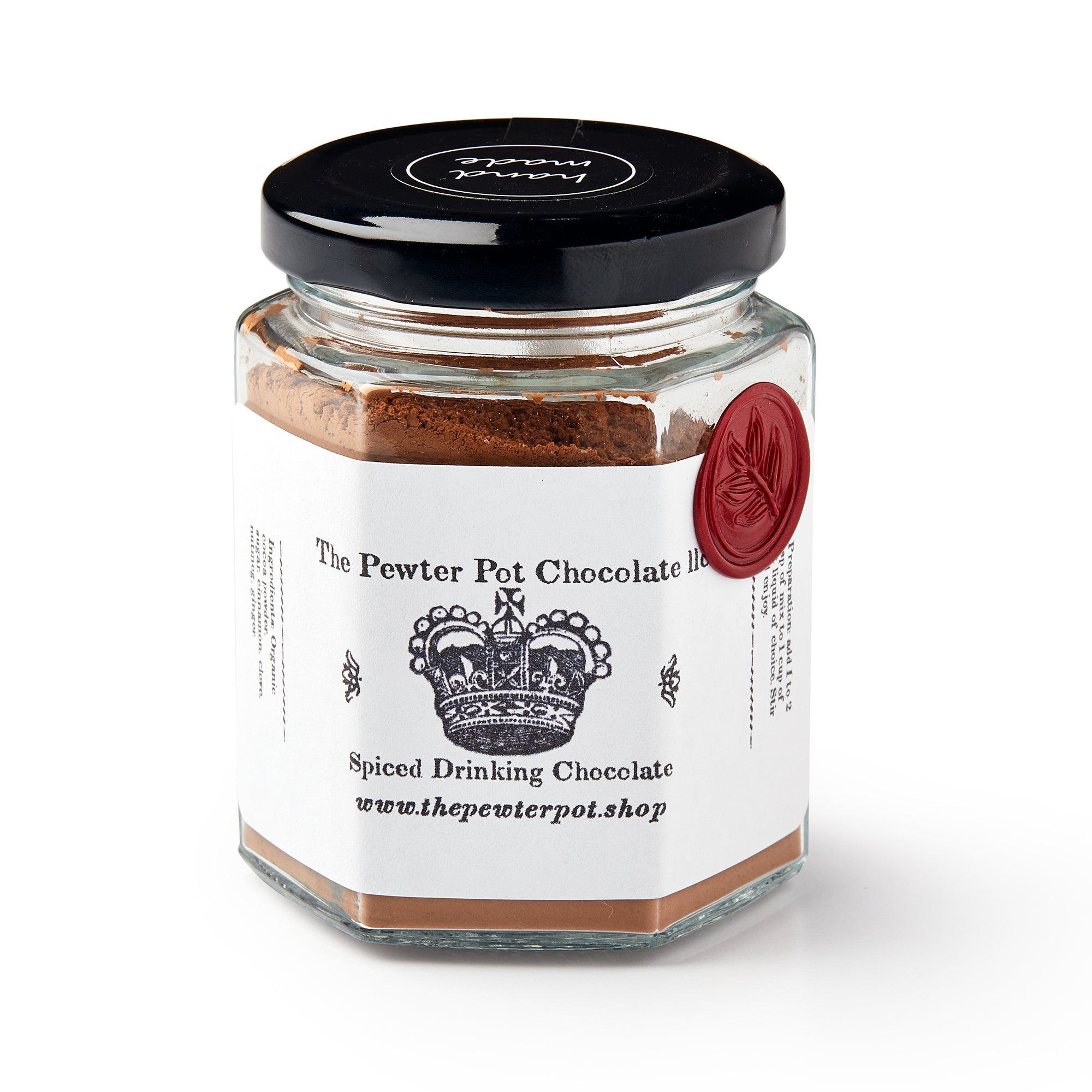 A hexagonal glass jar with a black lid filled with Drinking Chocolate. The label features a crown, red wax seal, and reads The Pewter Pot Chocolate Ltd Spiced Drinking Chocolate, evoking historic colonial chocolate.